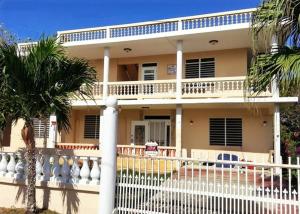 a house with a white fence and palm trees at Villa Marsana in Aguada