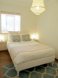 a bedroom with a large white bed with a chandelier at Pé N'Areia - Beach Apartment with Terrace in Viana do Castelo