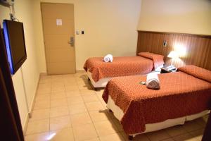 Habitación de hotel con 3 camas y TV de pantalla plana. en Hotel Confianza en Corrientes