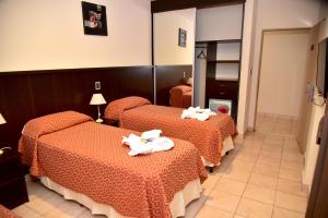 Habitación de hotel con 3 camas y toallas. en Hotel Confianza en Corrientes