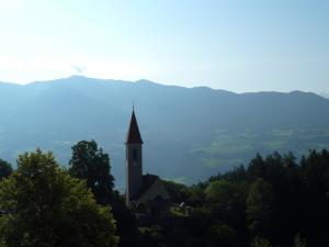 una chiesa in cima a una collina con alberi di Gasthof Weidmannshof a Bressanone