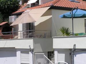 a white building with an umbrella and a balcony at Apartments Ella in Split