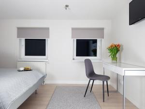 a bedroom with a bed and a desk and a chair at Chopin Apartments - Eco in Warsaw