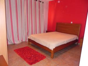 1 dormitorio con cama y pared roja en Lareira do Pinheirinho, en Charneca