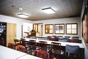 a dining room with chairs and tables in a room at Hakuba Cortina Backpackers in Otari