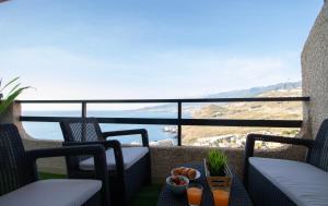 a balcony with two chairs and a table with fruit at Tabaiba Premier Views Apartment in Tabaiba