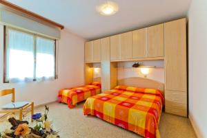 ビビオーネにあるApartment in Bibione 24425のベッドルーム1室(ベッド2台、キャビネット、テーブル付)