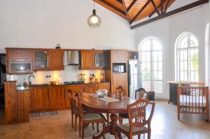 Una cocina con gabinetes de madera y una mesa con sillas. en Samindra Villa, en Kandy