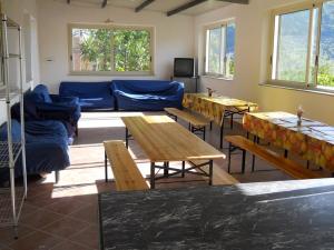 una sala de estar con sofás azules, mesas y ventanas en Apartments in Gioiosa Marea/Sizilien 23300 en Gioiosa Marea