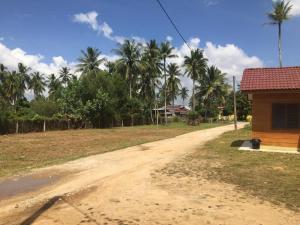 a dirt road next to a house with palm trees at Santai Lots Cherating in Kuantan