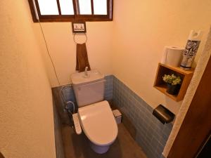 a small bathroom with a toilet with blue tiles at Inn the Camp in Kasaoka