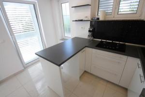 a kitchen with white cabinets and a black counter top at Crikvenica Apartment 24 in Dramalj