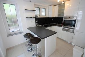 a kitchen with white cabinets and a black counter top at Crikvenica Apartment 24 in Dramalj