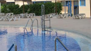 a swimming pool with a metal railing in the water at Apartamentos Europa House Sun Beach in Guardamar del Segura