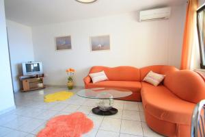 a living room with an orange couch and a tv at Two-Bedroom Apartment Crikvenica near Sea 6 in Dramalj