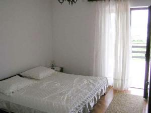 a white bedroom with a bed and a window at Apartment Pasman 1 in Pašman