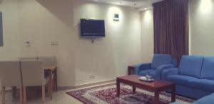 a living room with two blue chairs and a tv at Mani VIP Suites in Al Khobar
