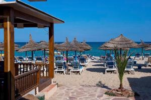 a beach with chairs and umbrellas and the ocean at Diar Lemdina Hotel in Hammamet