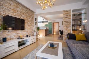a living room with a couch and a tv on a brick wall at Pansion Tina in Šilo