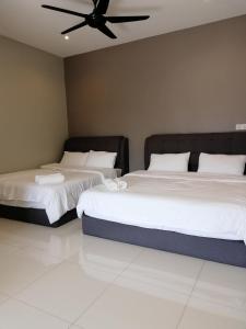 two beds in a bedroom with a ceiling fan at One Plus One Boutique Residence in Kuantan