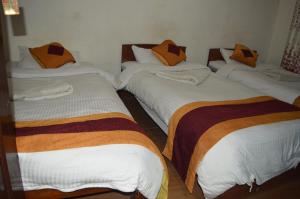 three beds with orange pillows on them in a room at Holyland Guest House in Kathmandu