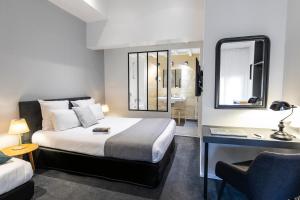 a bedroom with a bed and a desk and a chair at Hôtel La Cour Carrée Bordeaux Centre in Bordeaux