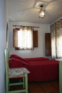 1 dormitorio con cama roja y ventana en Hostal Rural Las Terrazas de la Alpujarra en Bubión