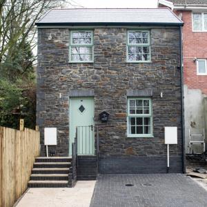 a brick house with a blue door and stairs at Ash Cottage in Merthyr Tydfil