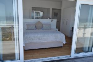 a bedroom with a bed and a sliding glass door at Thyme & Tide Beach Villa in Yzerfontein