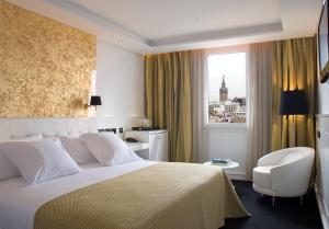 a hotel room with a bed and a chair and a window at Hotel Colón Gran Meliá - The Leading Hotels of the World in Seville