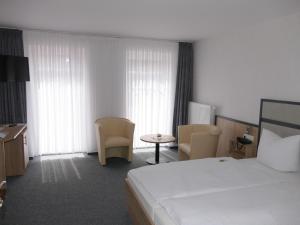 um quarto de hotel com uma cama, uma mesa e cadeiras em Hotel Diekgerdes, Komfortzimmer em Cloppenburg