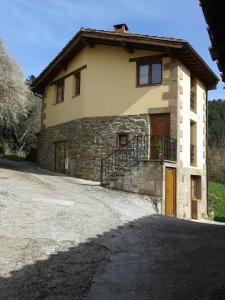 een groot stenen huis met een deur en een balkon bij Casa Rural LA HUERTA DE POTES in Cabezón de Liébana