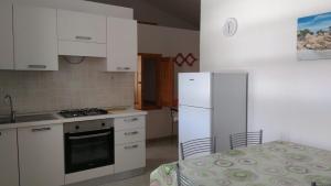 a kitchen with white cabinets and a white refrigerator at Budoni Apartments in Budoni