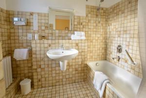 La salle de bains est pourvue d'un lavabo et d'une baignoire. dans l'établissement Cit'Hotel Aéro-Hotel, au Blanc-Mesnil