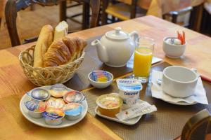 a table with breakfast food and a basket of bread and orange juice at Cit'Hotel Aéro-Hotel in Le Blanc-Mesnil