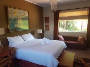 a bedroom with a large white bed and a window at Burnham Road Suite Guest House in Bulawayo