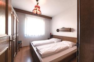 ein kleines Schlafzimmer mit einem Bett und einem Fenster in der Unterkunft Sonnen Residence in Klobenstein