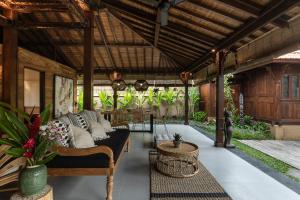 - un salon extérieur avec un canapé et des tables dans l'établissement Villa Niyamas Ubud, à Ubud