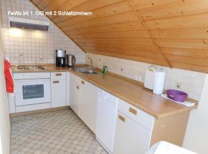 eine Küche mit weißen Geräten und einer Holzdecke in der Unterkunft Ferienwohnung "Am Muschwitztal" Bad Steben / Carlsgrun in Bad Steben