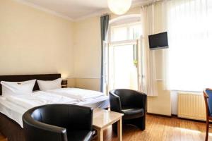 een slaapkamer met een bed en 2 stoelen en een tafel bij Hotel Silesia in Görlitz
