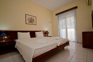 a bedroom with a bed with white sheets and a window at Stella Hotel in Pefki