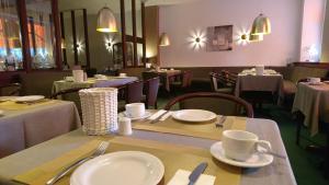 a restaurant with tables and chairs with white plates and cups at Hotel Deutschherrenhof in Trier