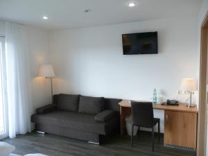 uma sala de estar com um sofá e uma escrivaninha em Gasthof Brennerei zum Forst em Kressbronn am Bodensee