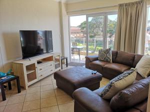 a living room with couches and a flat screen tv at Seahorse unit 4 in Scottburgh
