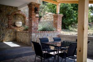 a patio with a table and chairs and a stone wall at VILLA LIDIA in Mundanije