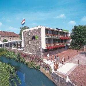 a building with people walking in front of a river at Marx Motel in Valkenburg