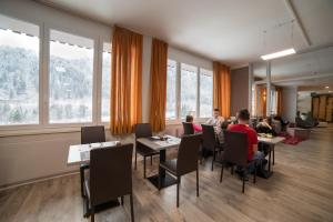 a group of people sitting at tables in a room with windows at Hotel Alla Fonte in Arta Terme