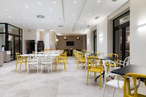 a dining room with tables and yellow chairs at Hotel Forum Garni in Subotica