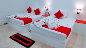 2 camas en una habitación con rojo y blanco en Roshanne Beach Resort, en Kalpitiya