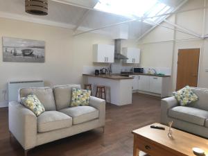 a living room with two couches and a kitchen at Ice House Apartments in Swansea
